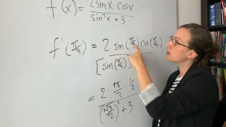 Photo of a woman in front of a white board teaching mathematics